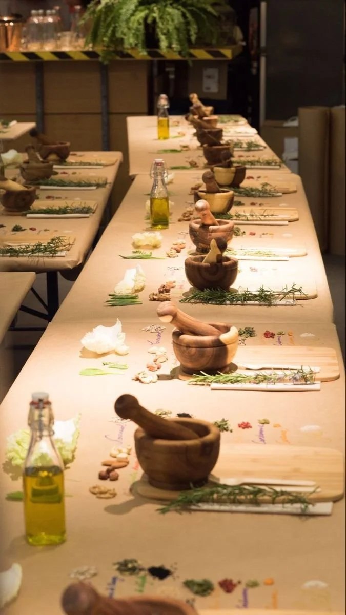 A long dining table set up for a cooking or tasting event, with wooden mortars and pestles