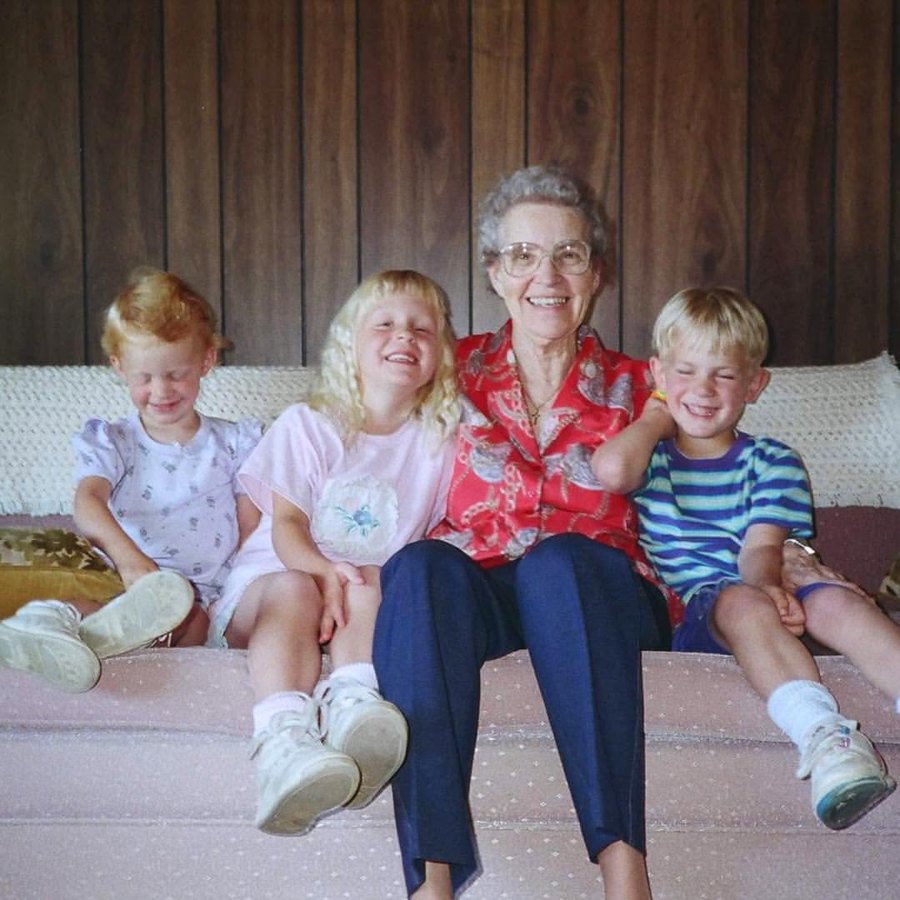 Vintage family photo of a smiling grandmother on a couch with three laughing young grandchildren